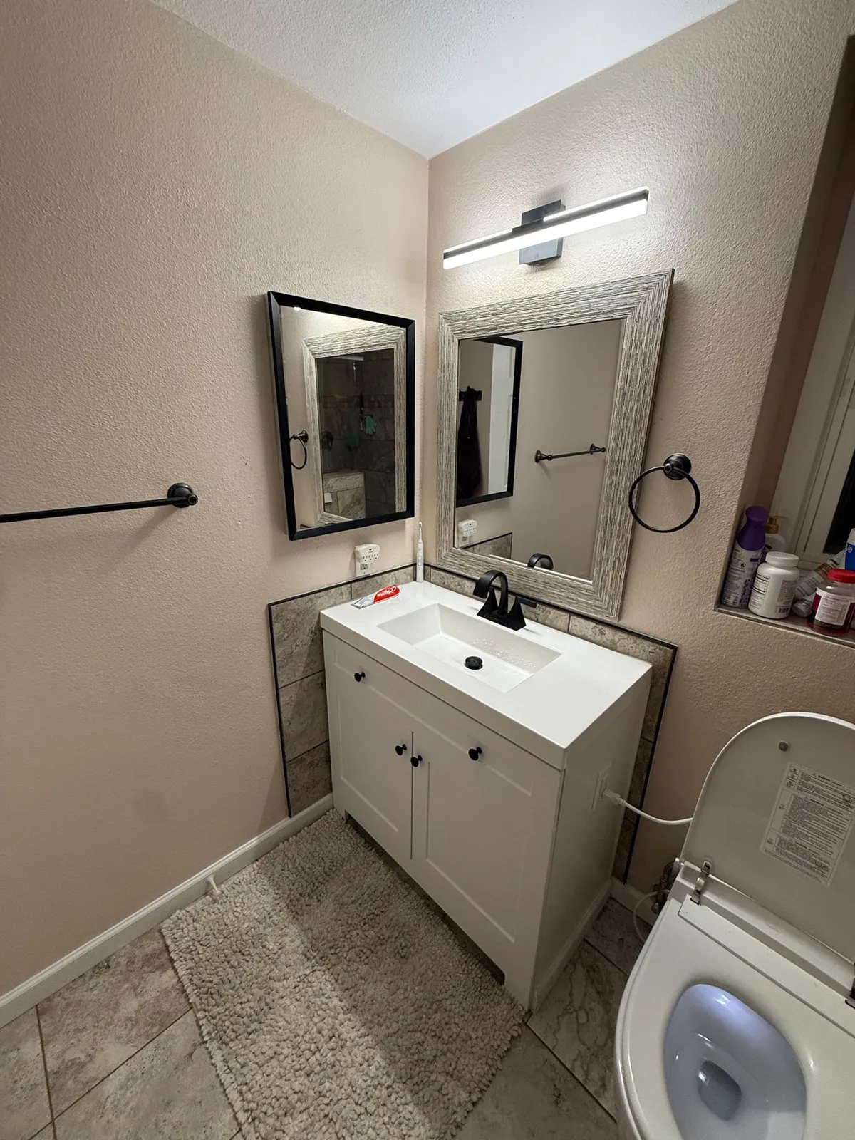 Bathroom upgrade with new mirrors, vanity light, and matte-black fixtures