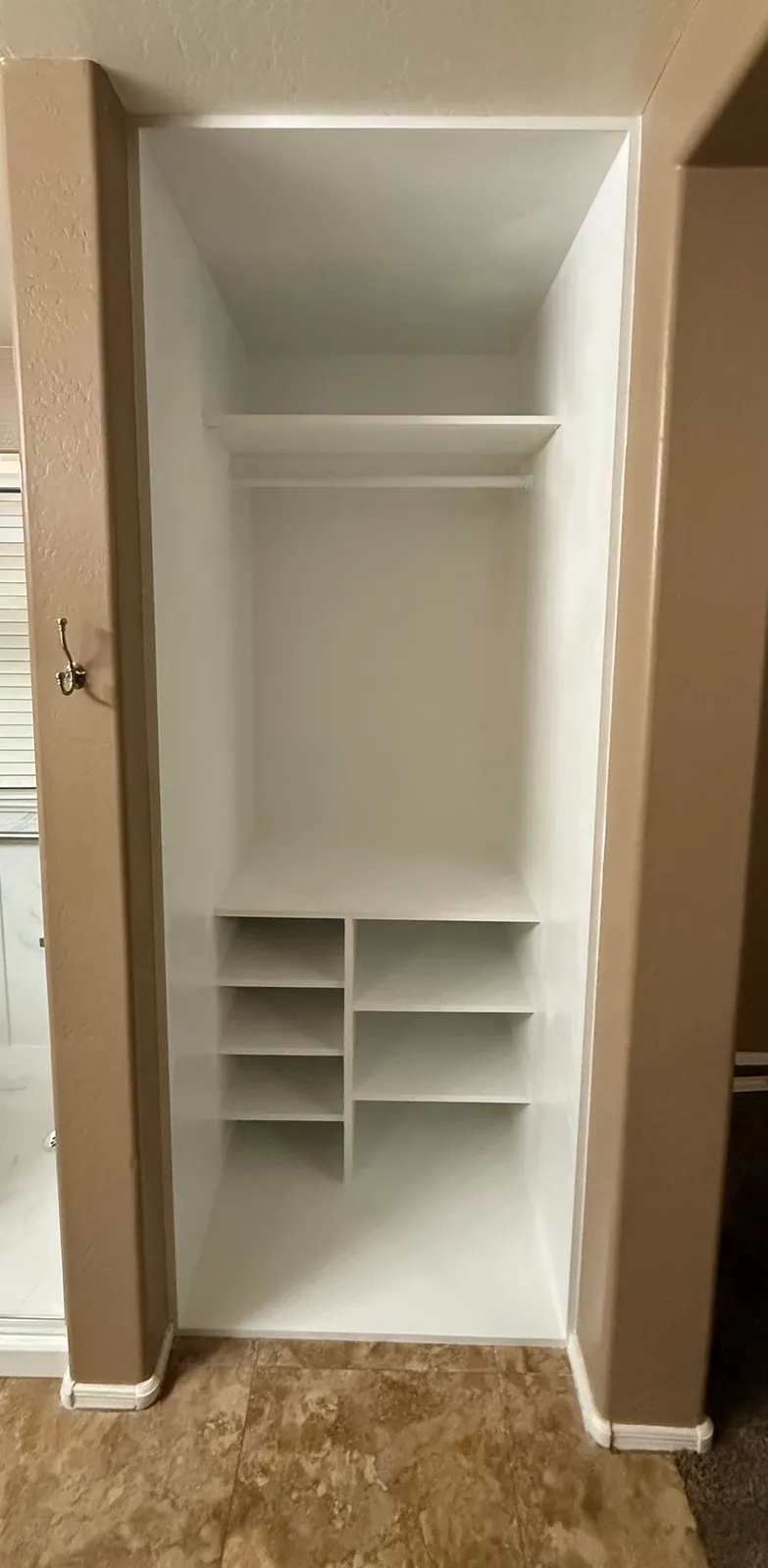 Finished custom closet with hanging rod and built-in shelving where the shower stall was