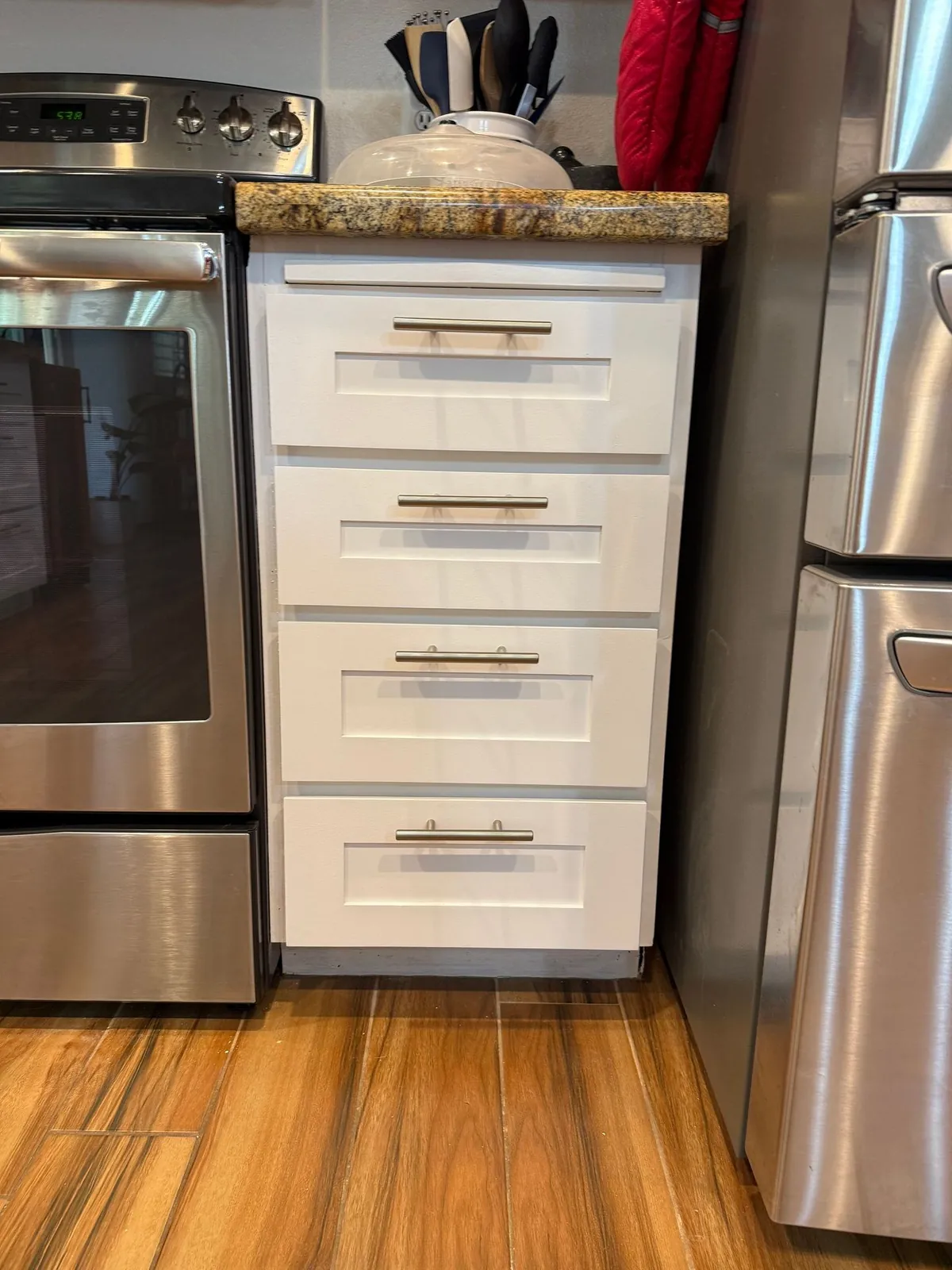 New white shaker cabinet drawers installed under a granite countertop
